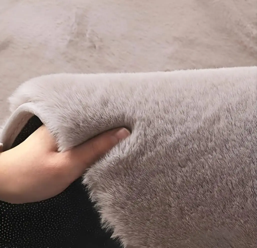Soft faux rabbit fur carpet placed beside bed in cozy bedroom by Prisha Cart